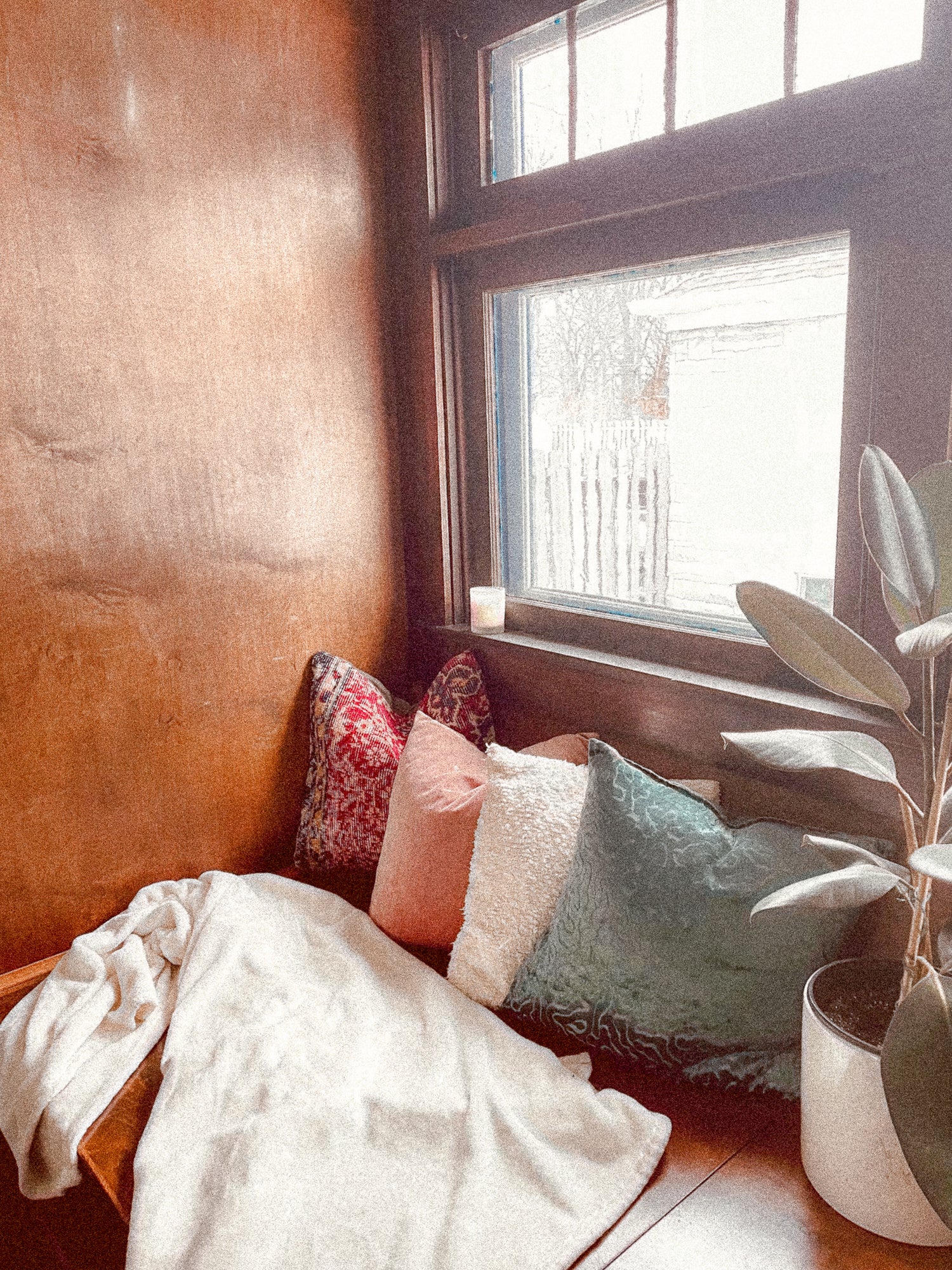 reading nook with wood panelling walls near a window with plants and pillows